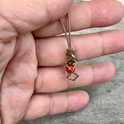 魔を除ける意味の赤珊瑚を、真鍮のサークルで包んだ小ぶりの一粒