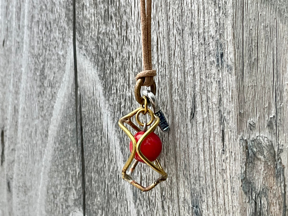 魔を除ける意味の赤珊瑚を、真鍮のサークルで包んだ小ぶりの一粒