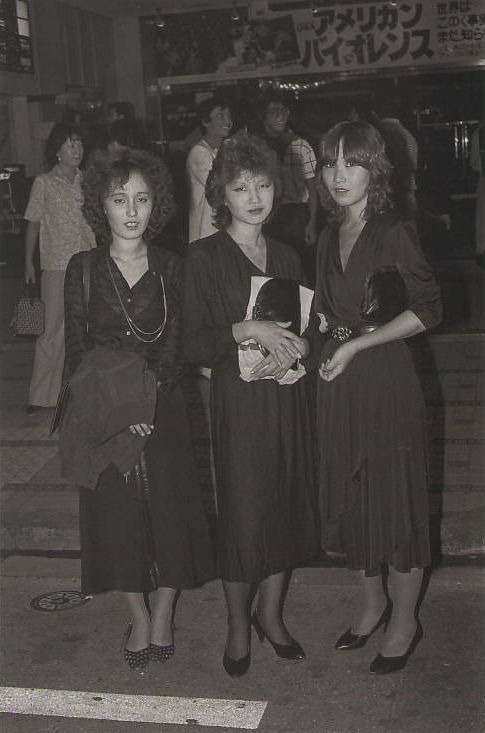 新宿歌舞伎町。女性の後ろ「アメリカン・バイオレンス」は1981年公開